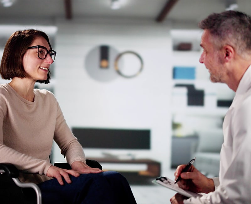 Doctor And Female Patient In Wheelchair At Home
