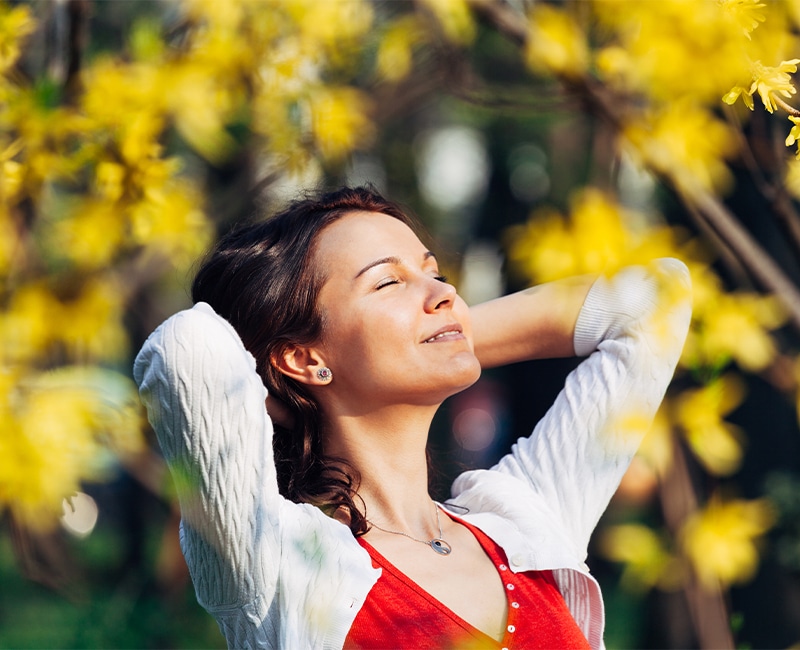 Kentucky Women behind leafs with arms holding her hair looking at the sun