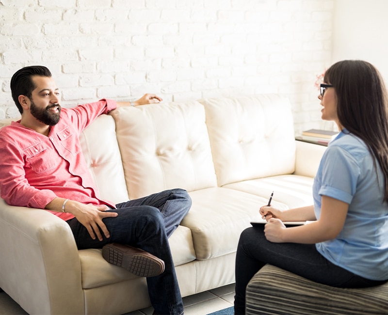 Happy and relaxed young hispanic man listening to psychologist after recovering from substance abuse