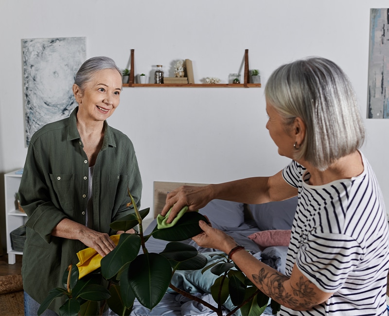 A senior cleans their modern apartment together, smiling at each other as they work Improving Quality of Life in Senior Facilities