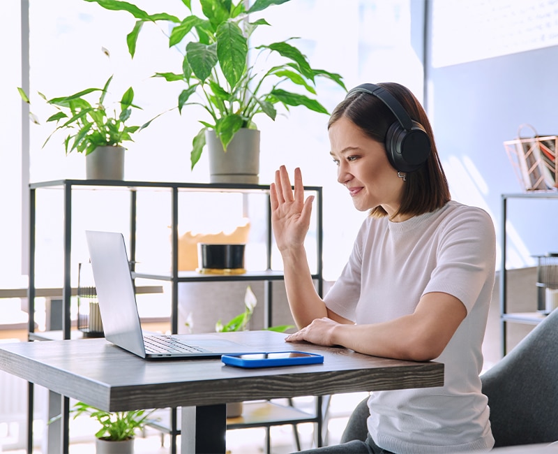 Young woman in headphones having video chat conference using laptop sitting in cafe