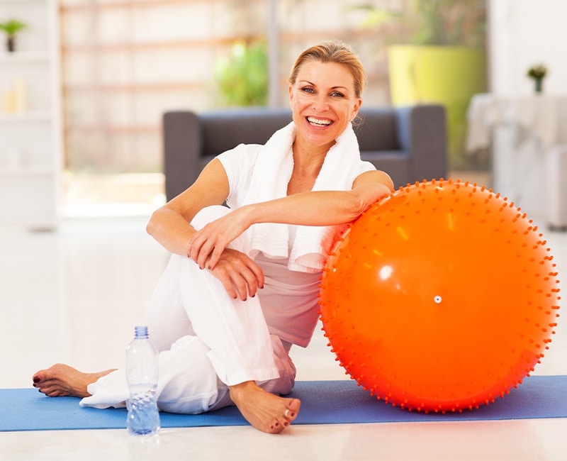 happy senior woman resting on mat after exercise at home