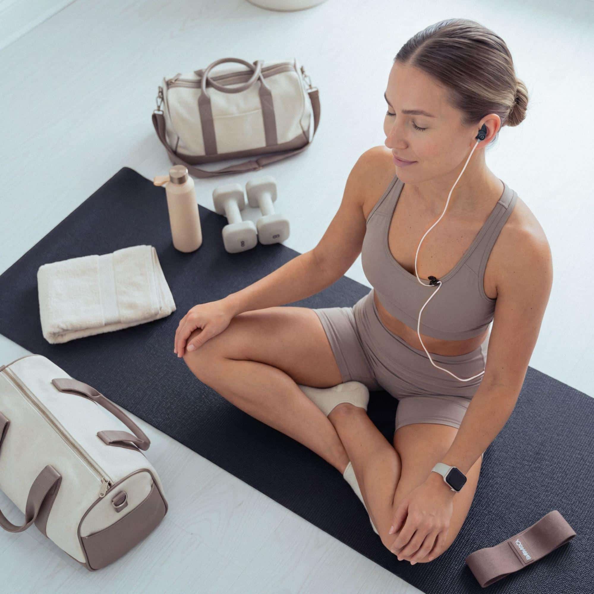 Kentucky Counseling Center | Why Everyday Stress Can Leave You Mentally Foggy Woman seated on an exercise mat while wearing an ear-worn device
